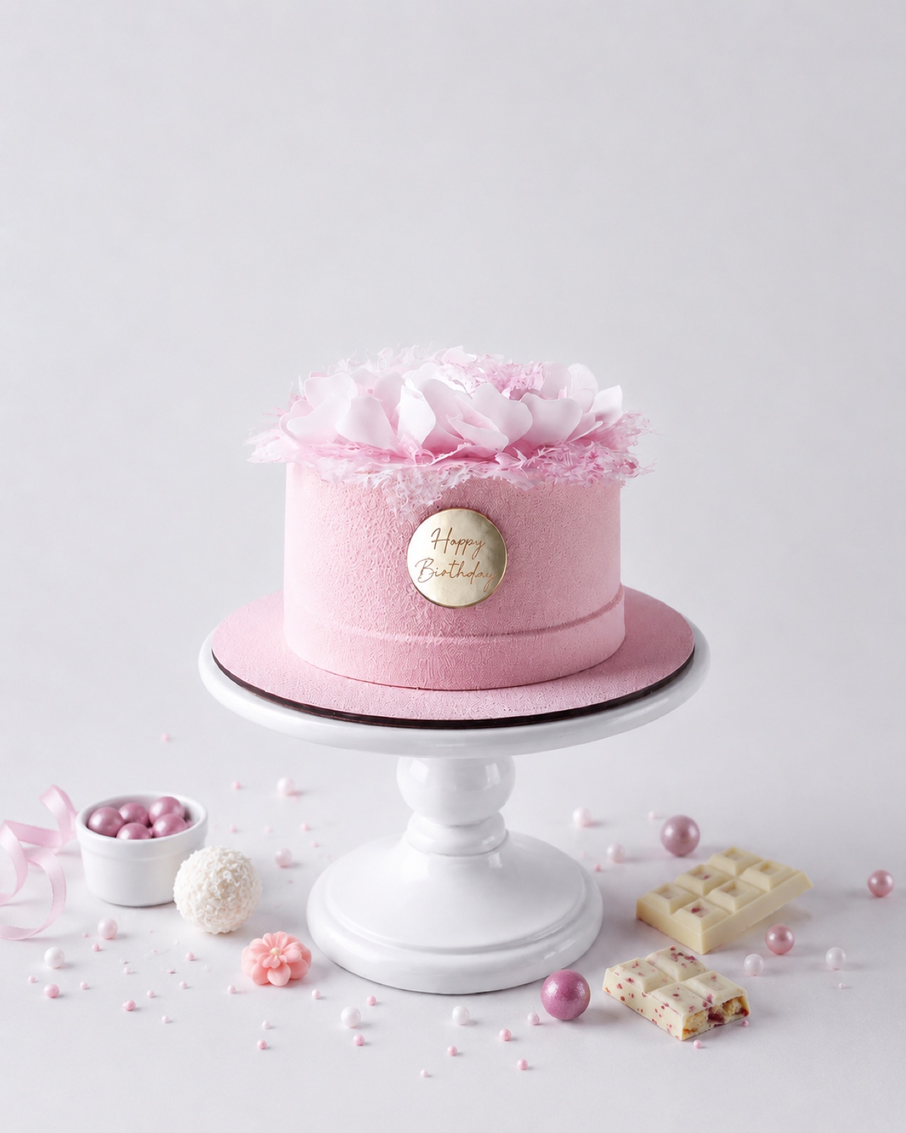 A bespoke pink cake with sugar flowers and Happy Birthday medallion
